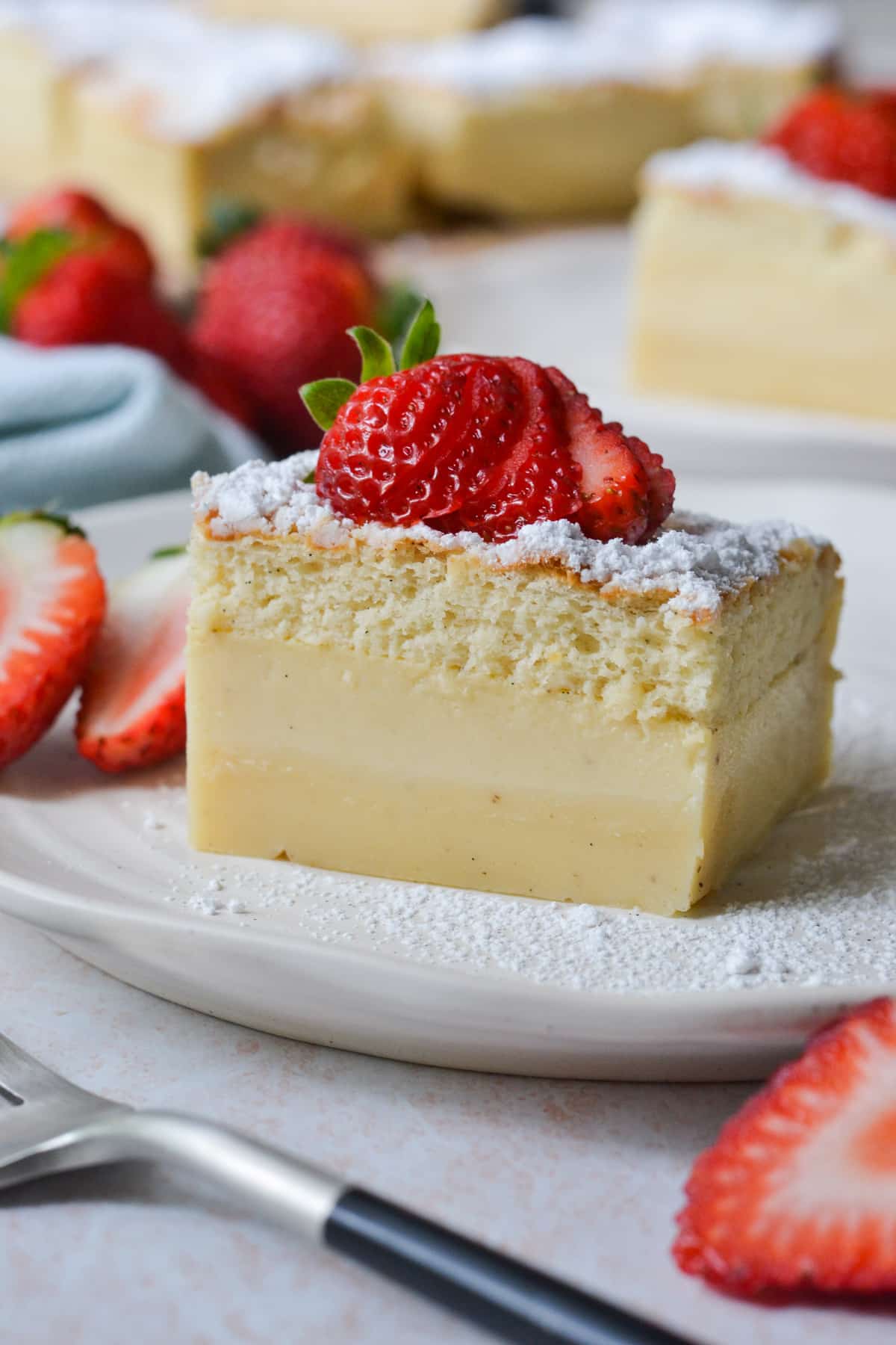 a slice of custard cake on a white plate with strawberries