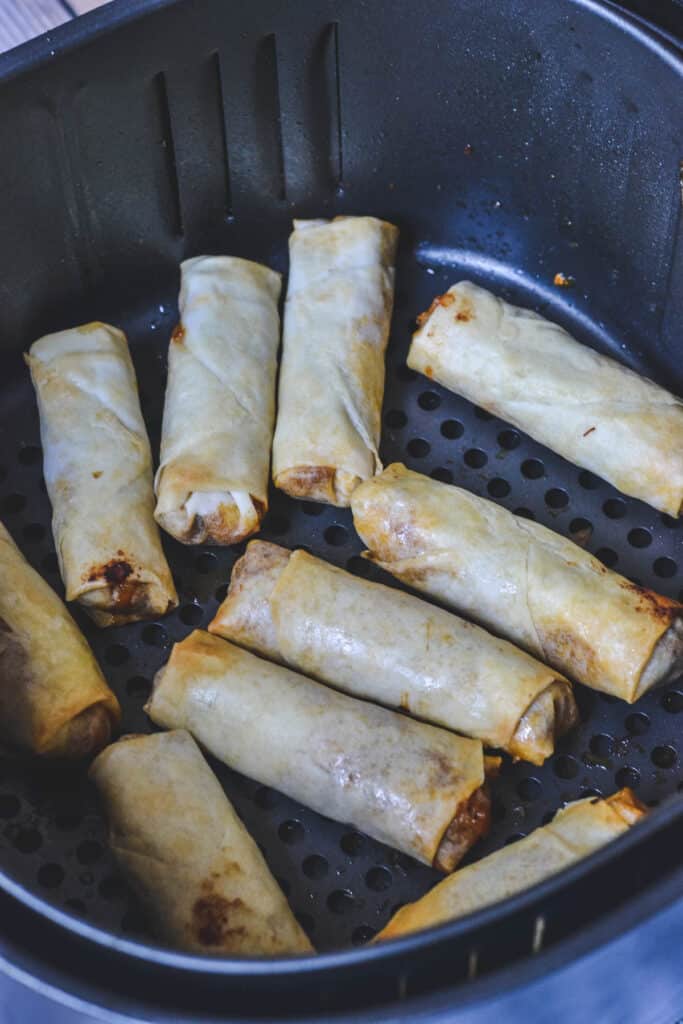 golden spring rolls in an air fryer basket