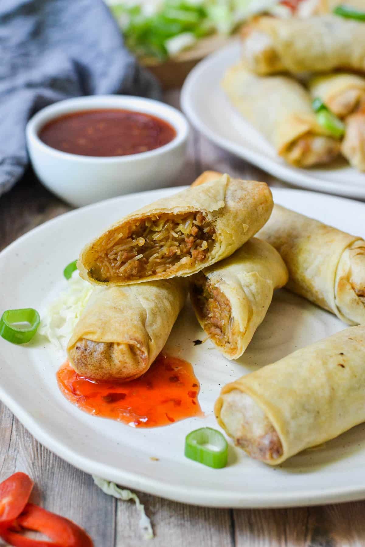 spring rolls on a white plate with pork and sweet chilli sauce
