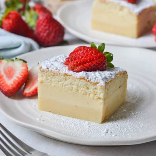 close up of a slice of custard cake on a white plate with strawberries