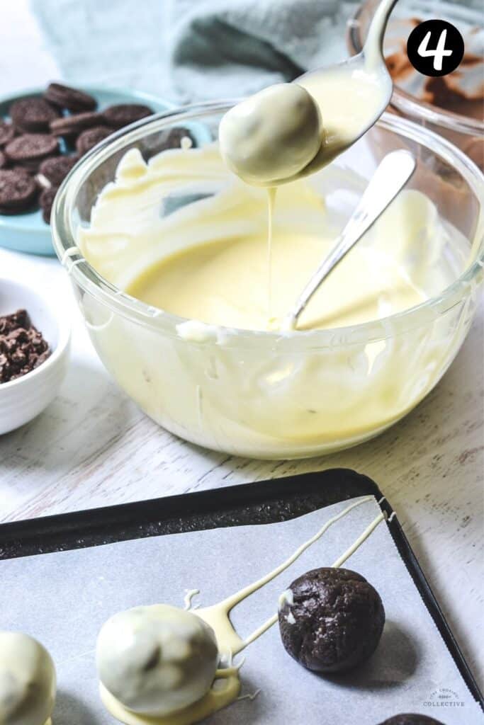 a spoon dipping an oreo ball in melted white chocolate