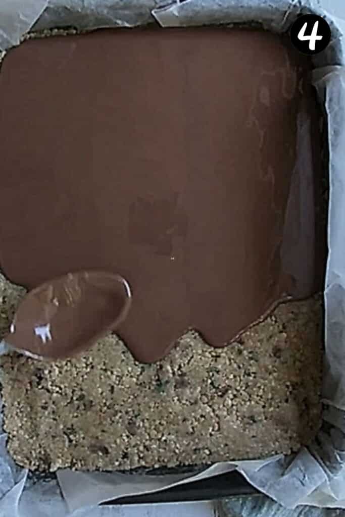 melted chocolate being spread over the top of mint slice in a tin