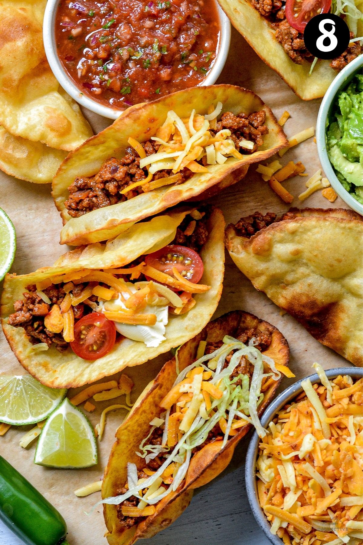 assembled taco shells topped with cheese, tomatoes and salad