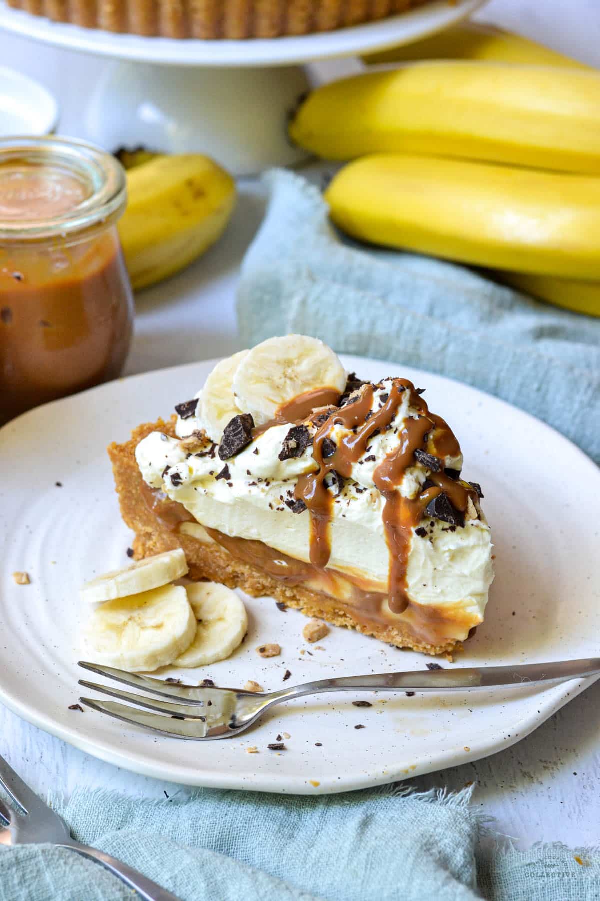 a piece of banoffee pie on a white plate with pieces of banana and cream