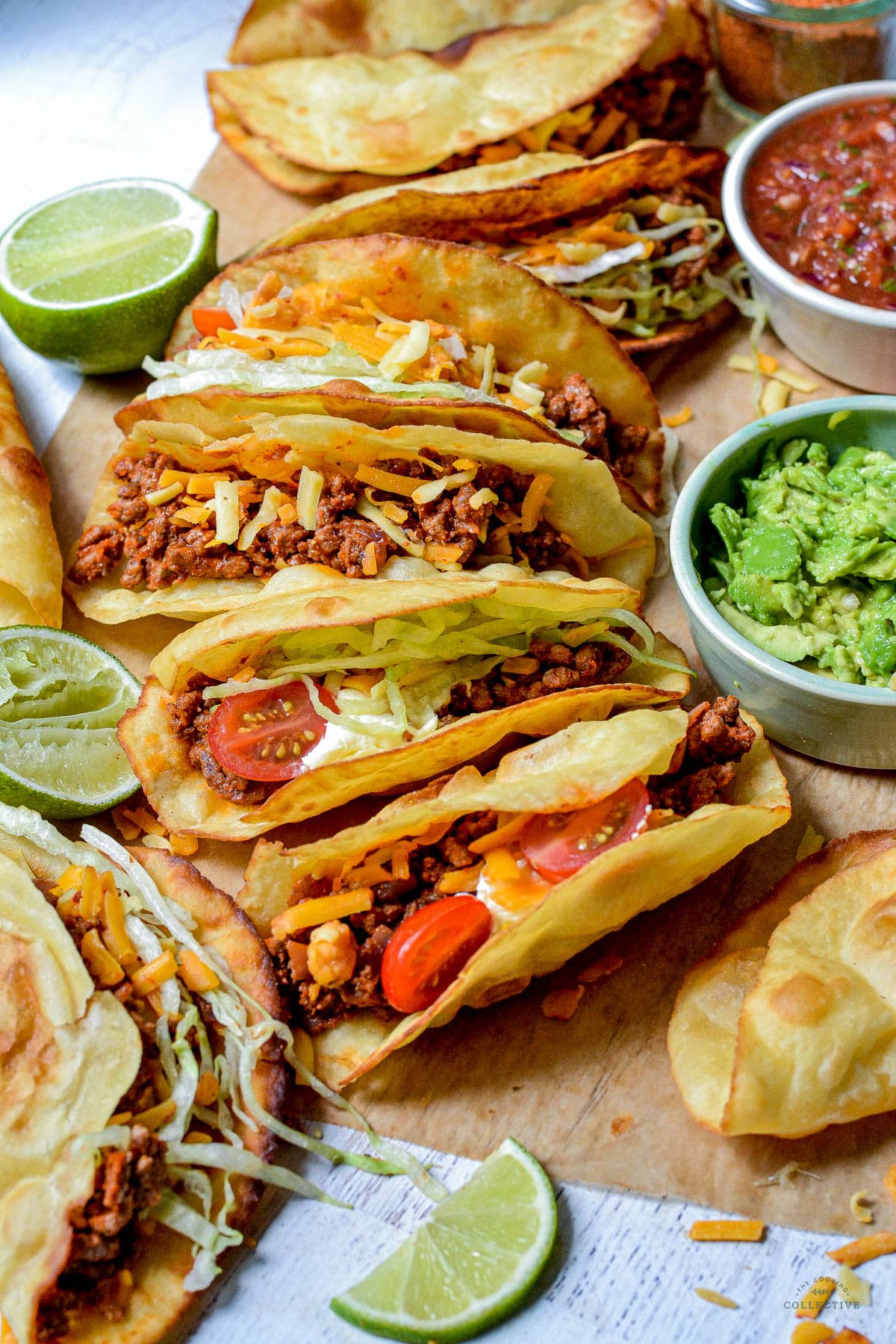 homemade beef tacos on a table with avocado and salsa