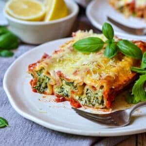 spinach and ricotta cannelloni on a plate with basil and cheese