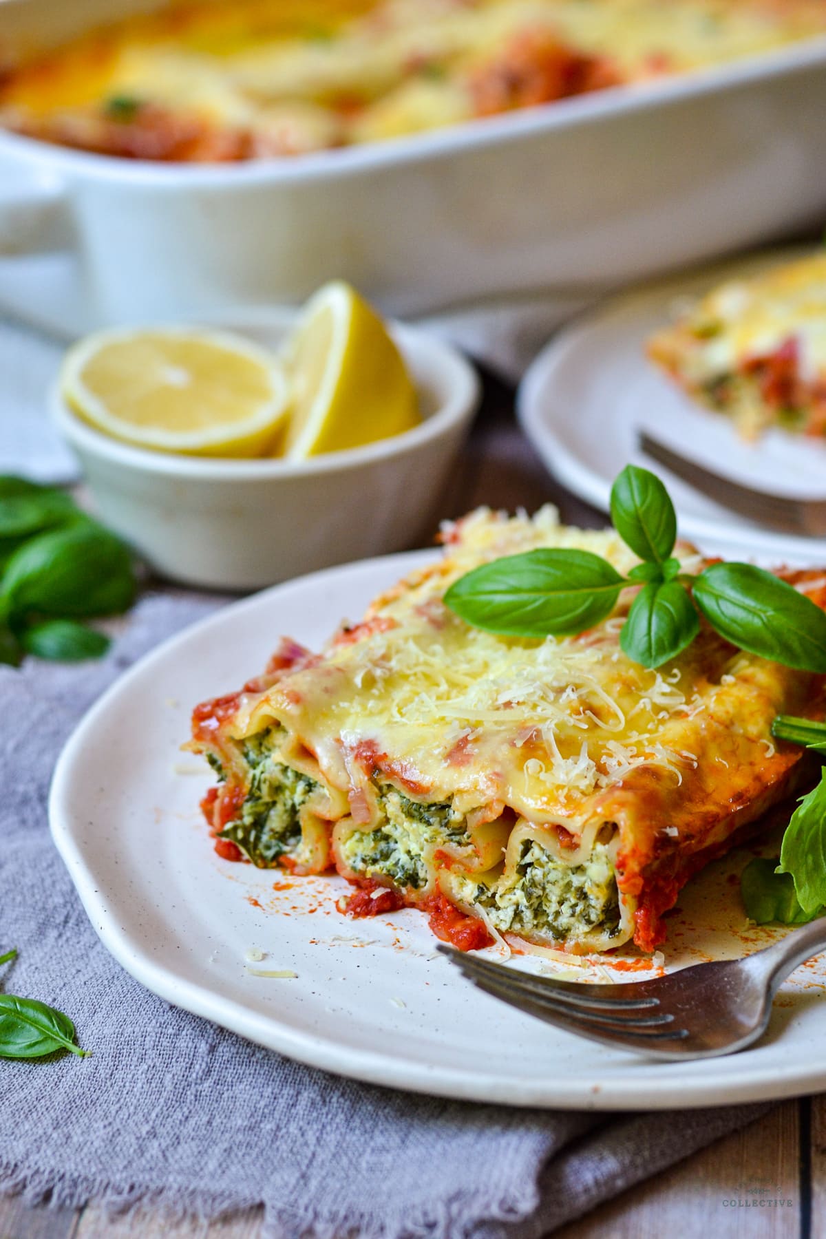 finished cannelloni arranged on a grey plate with melted cheese and basil