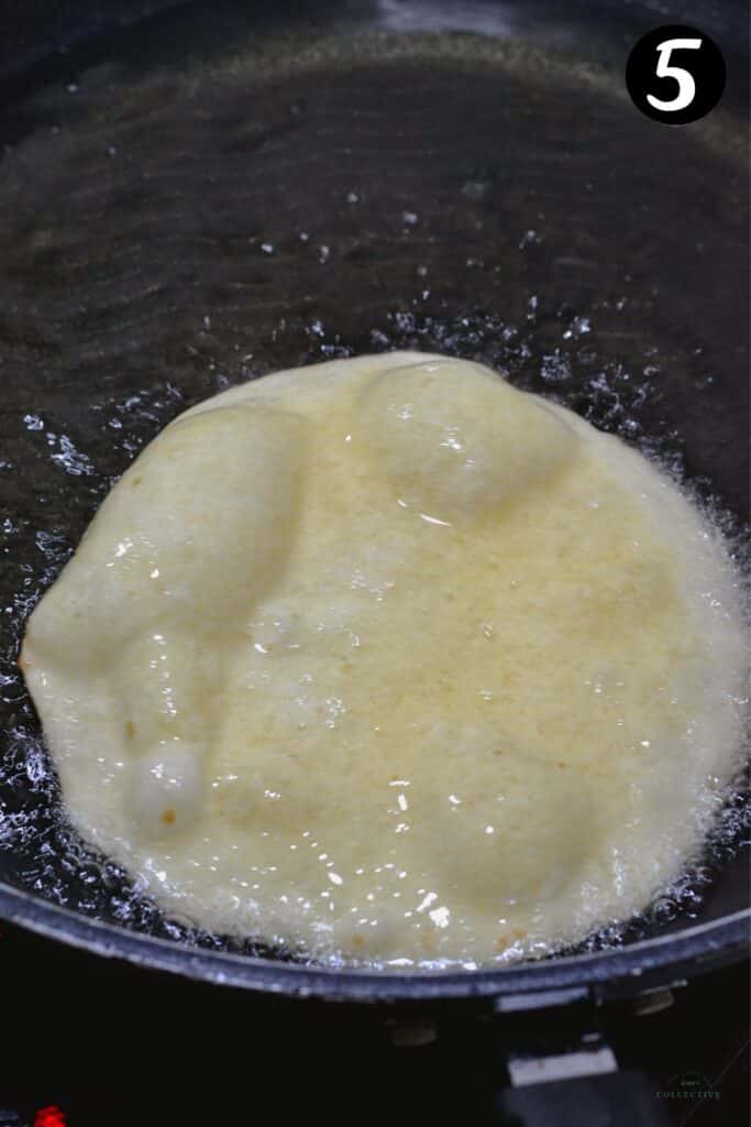 a corn tortilla frying in a pan of oil