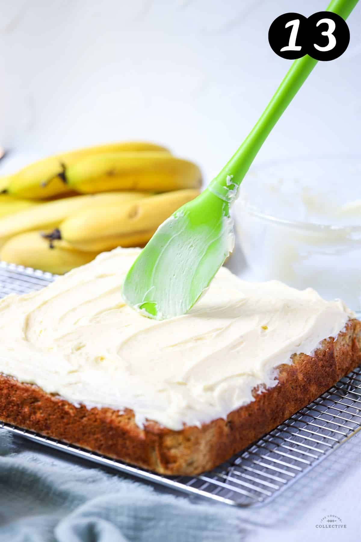 a spatula spreading cream cheese frosting over the top of a cake