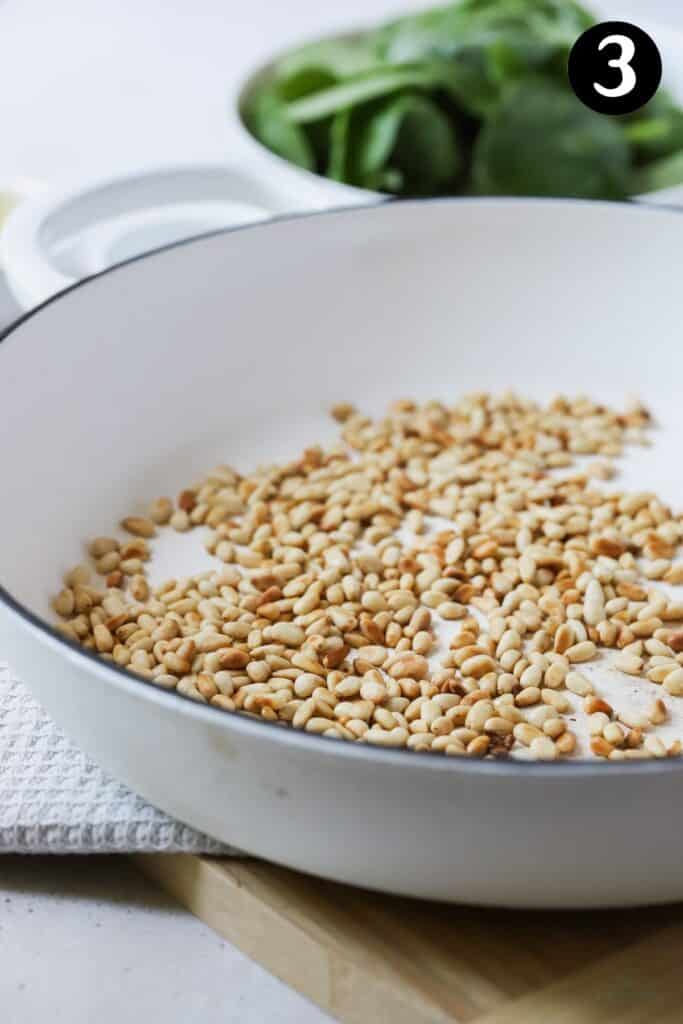 toasted pine nuts in a white pan