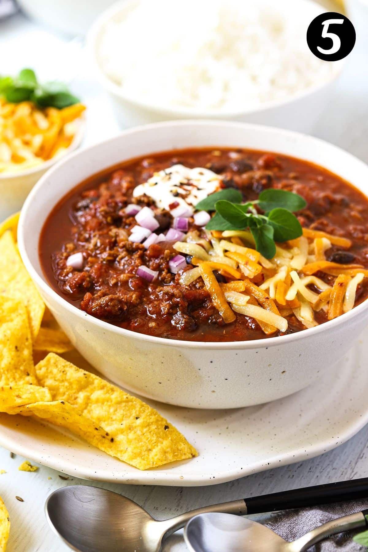 chilli con carne in a bowl topped with cheese and sour cream