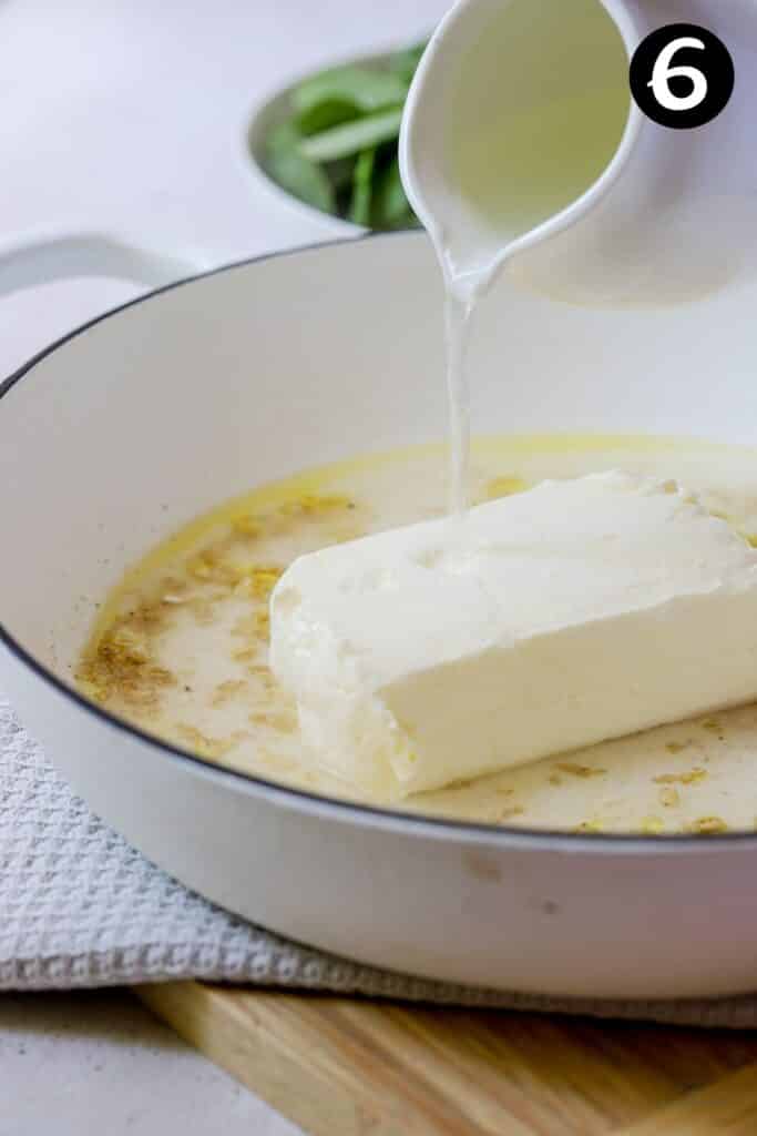 pasta water being poured over a block of cream cheese in a pan