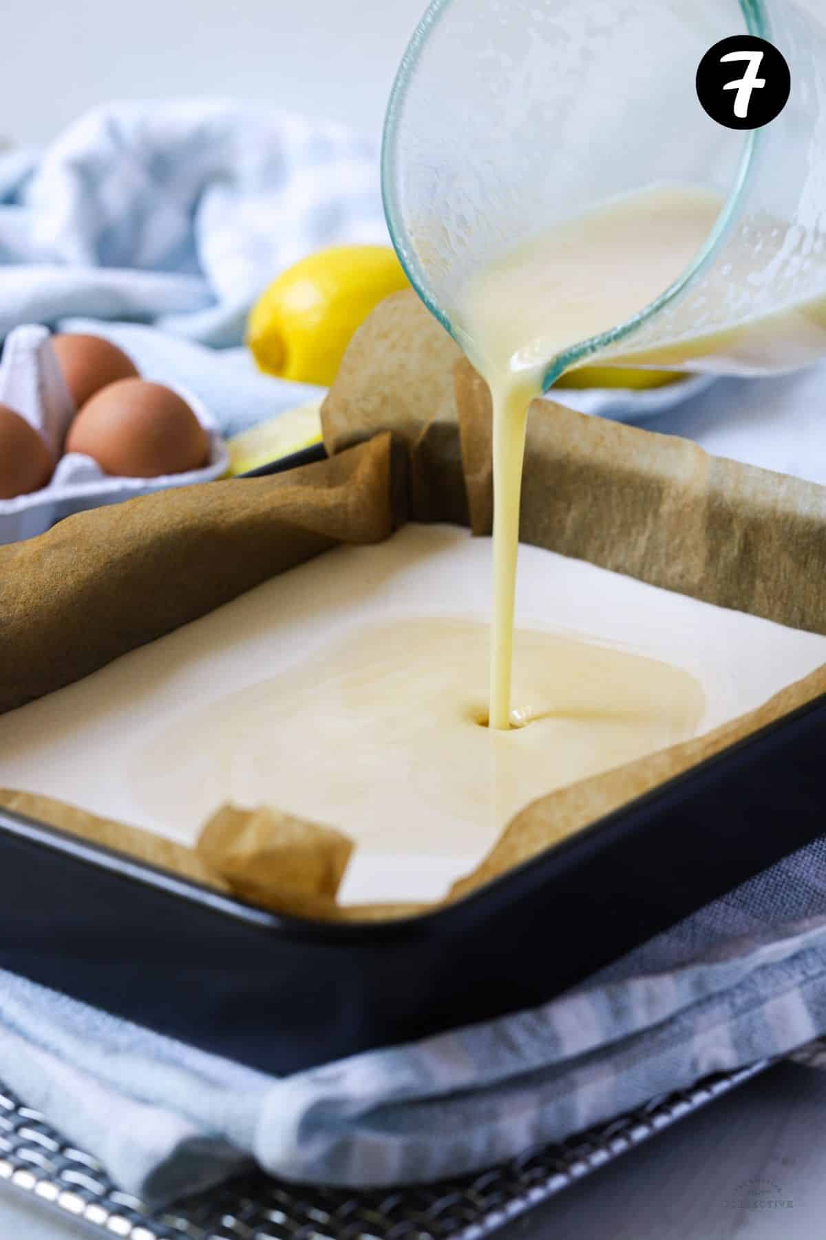 lemon mixture being poured over a shortbread base in a tin