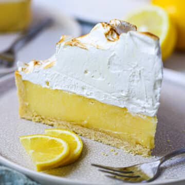 a slice of lemon meringue pie on a grey plate