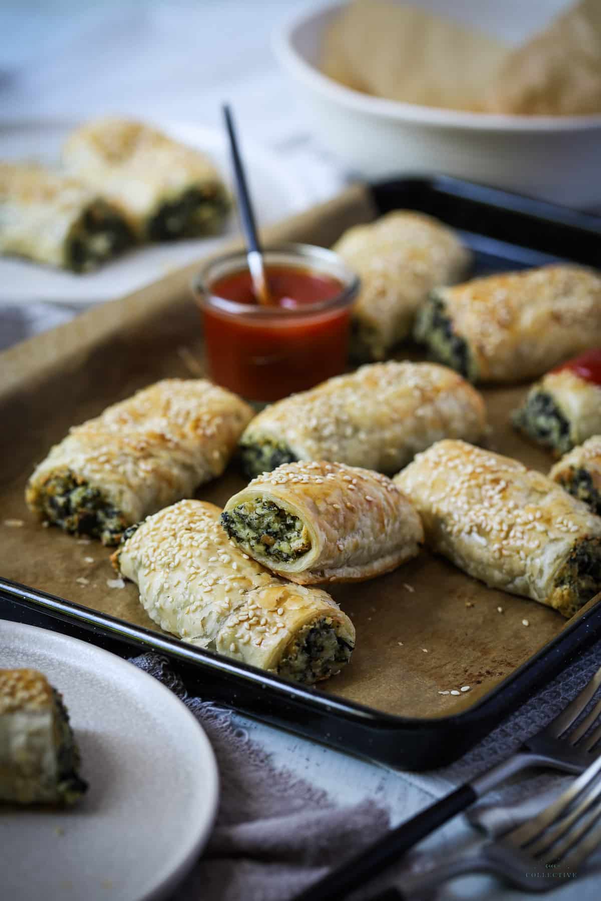 spinach and ricotta rolls on a baking tray with tomato sauce