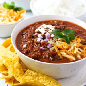 a bowl of chilli con carne topped with cheese and sour cream