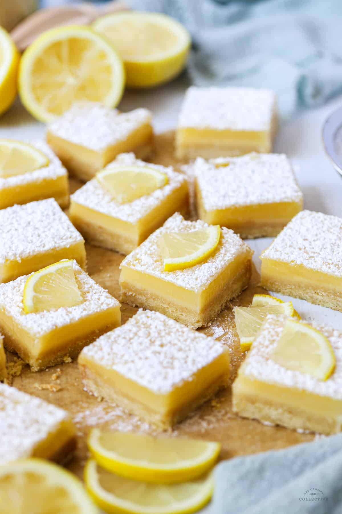 squares of meyer lemon bars topped with lemon wedges on a white table
