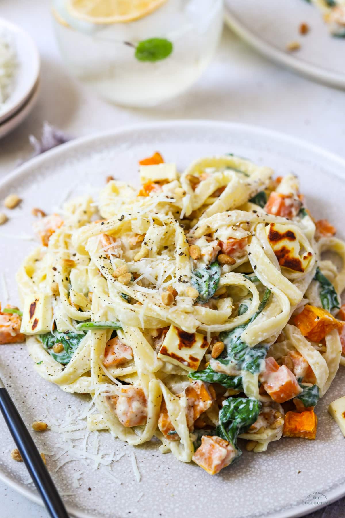cream cheese pasta on a grey plate with sweet potato and pine nuts