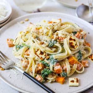 cream cheese pasta on a plate with sweet potato and pine nuts