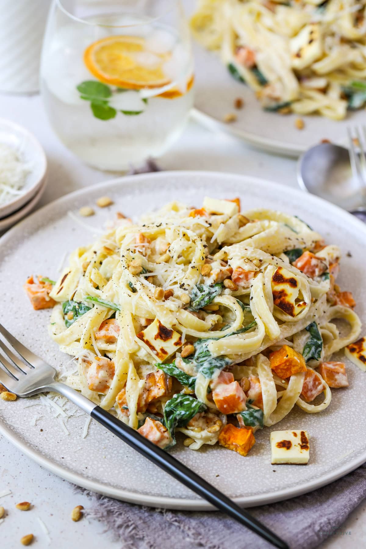 cream cheese pasta topped with sweet potato on a grey plate with a fork