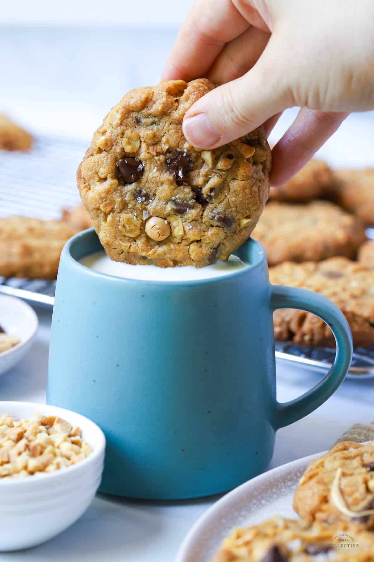 a hand dipping a cookie in a green mug filled with milk