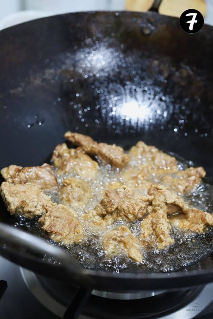 pork pieces frying in oil in a wok