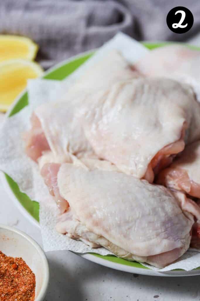 raw chicken thighs on a green plate on a paper towel