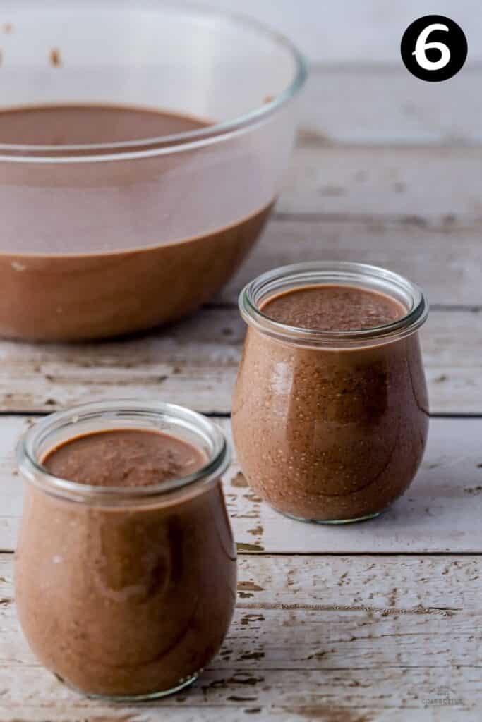 chia pudding added to individual jars on a wooden bench