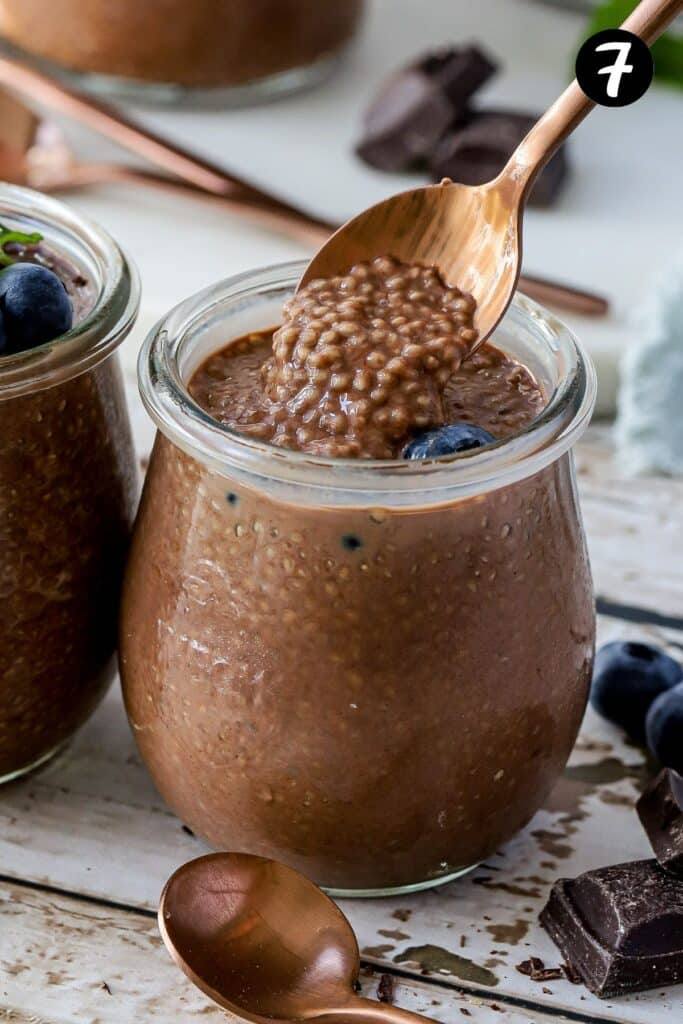 a spoon holding finished chia pudding over a jar