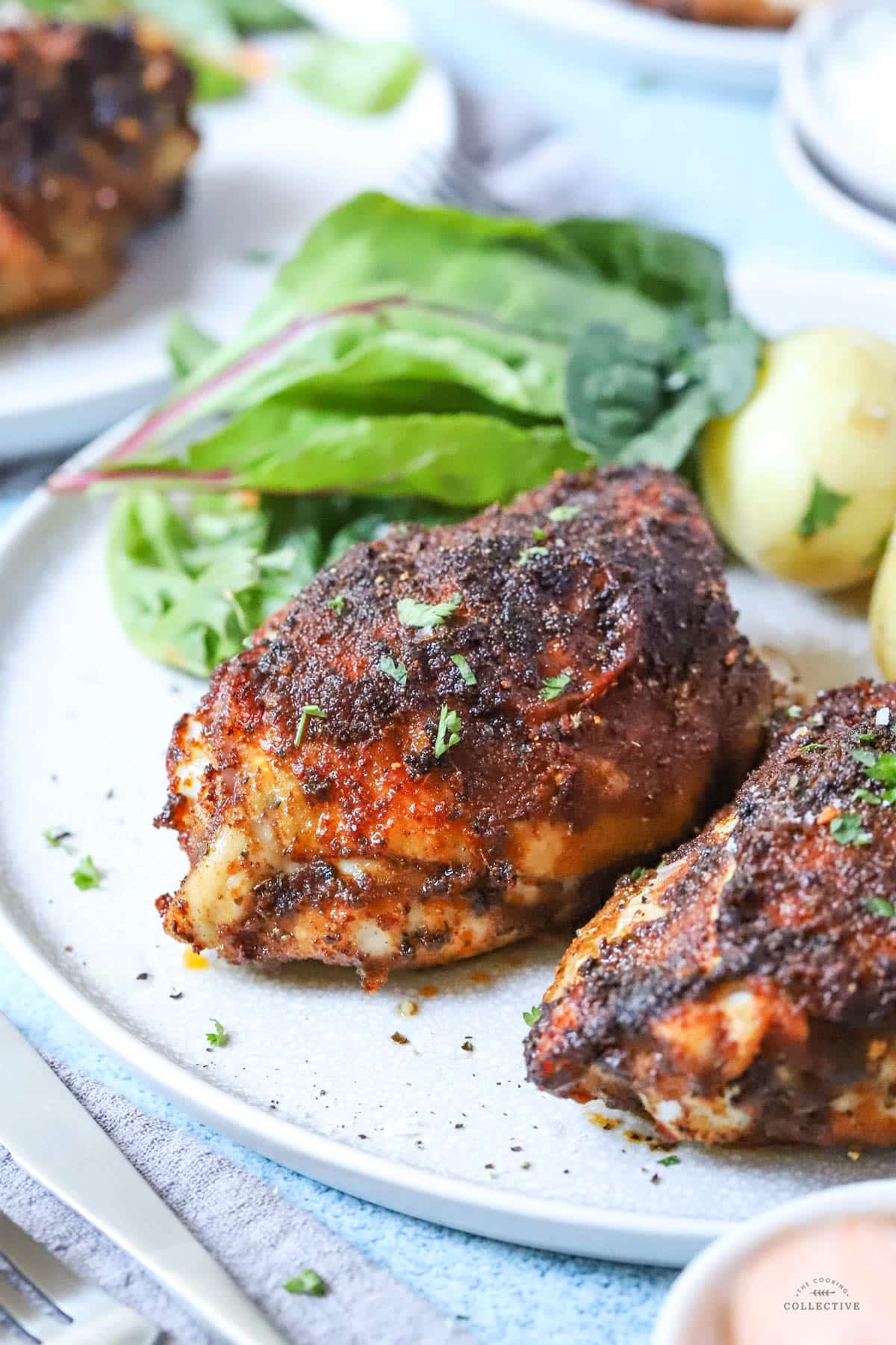 seasoned chicken thighs on a grey plate with salad