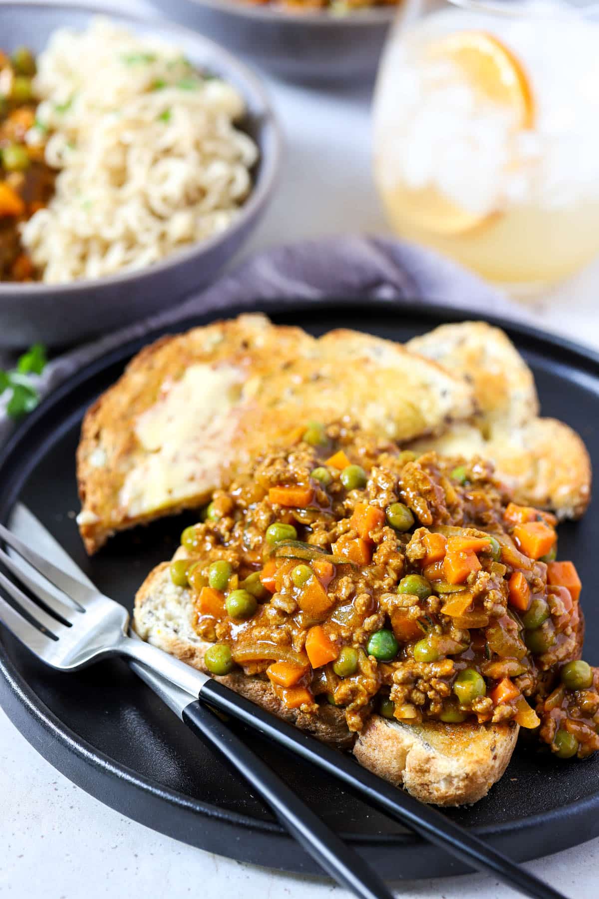 savoury mince with vegetables over a piece of buttered toast on a black plate