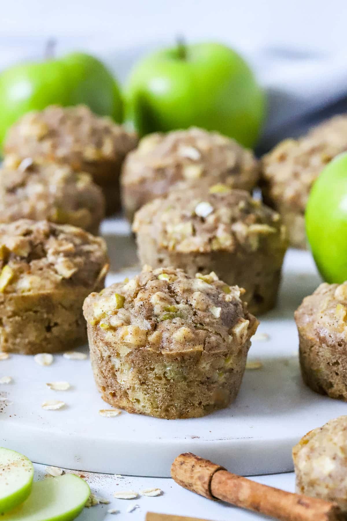 apple muffins on a plate with slices of apple and cinnamon sticks