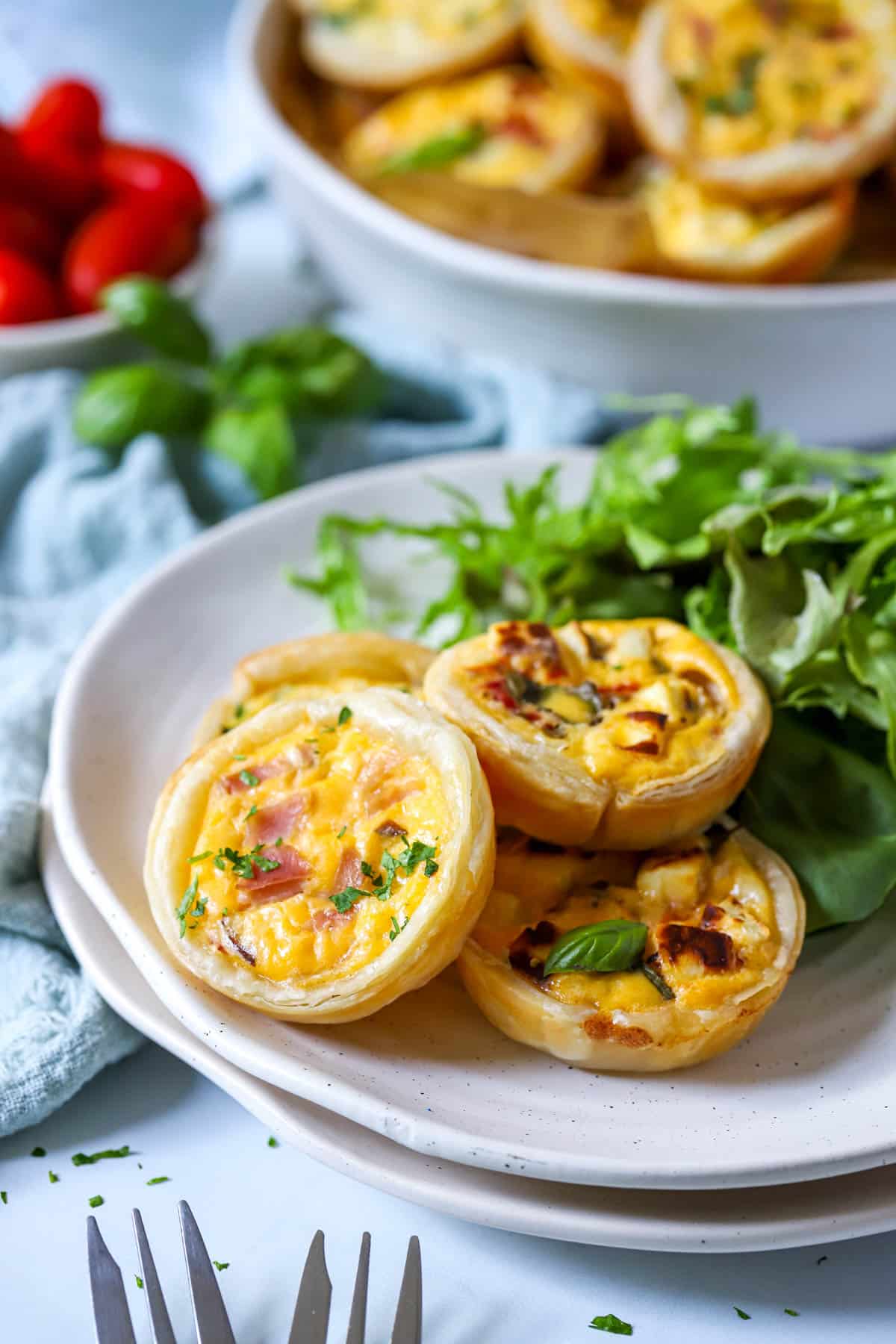 mini quiche arranged on a white plate with salad