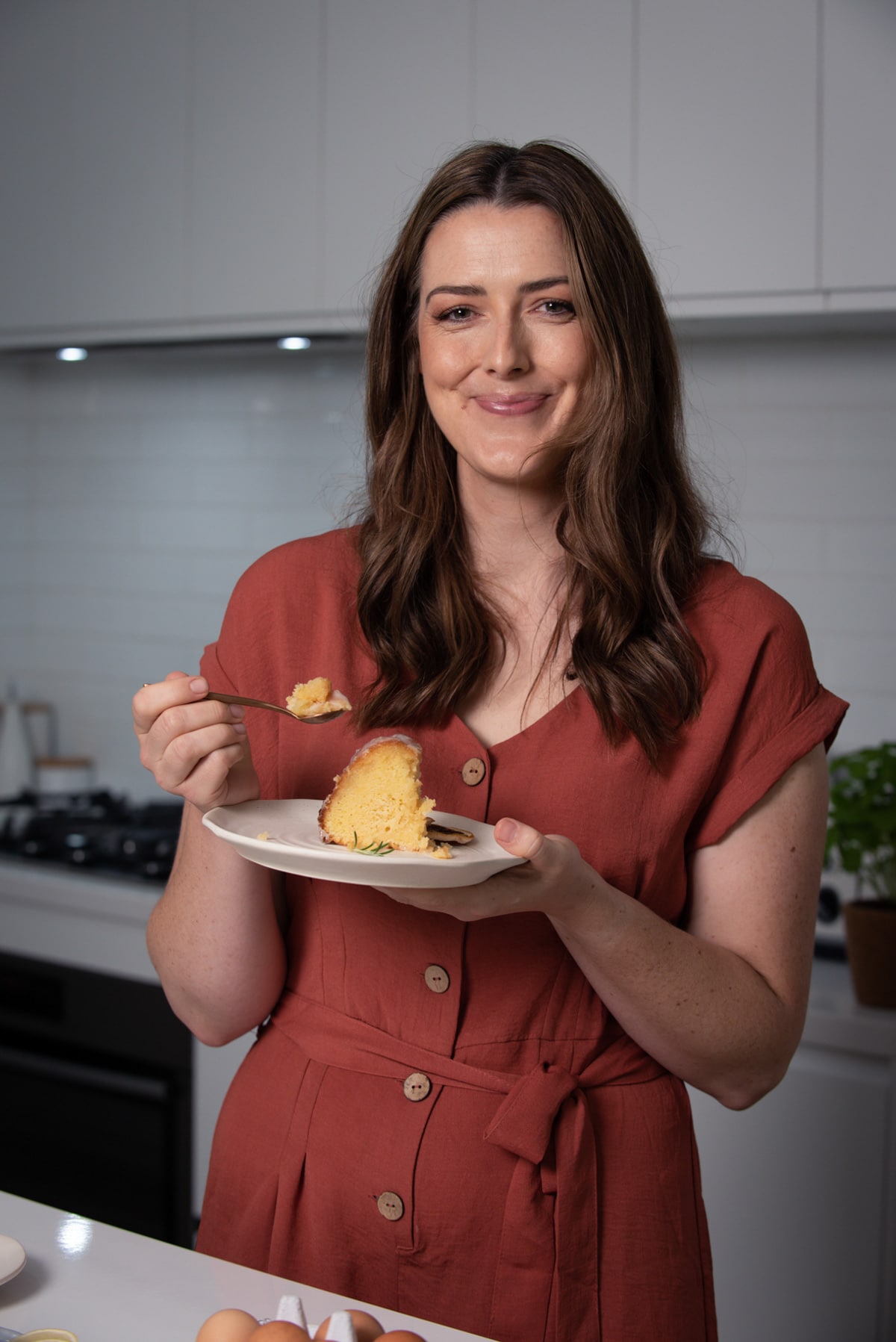 a photo of a smiling woman holding a plate with cake