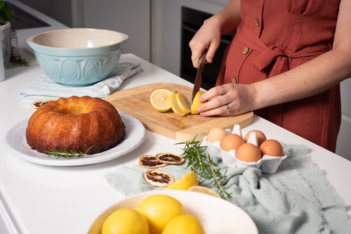 hands cutting a lemon on a bench with cake and eggs