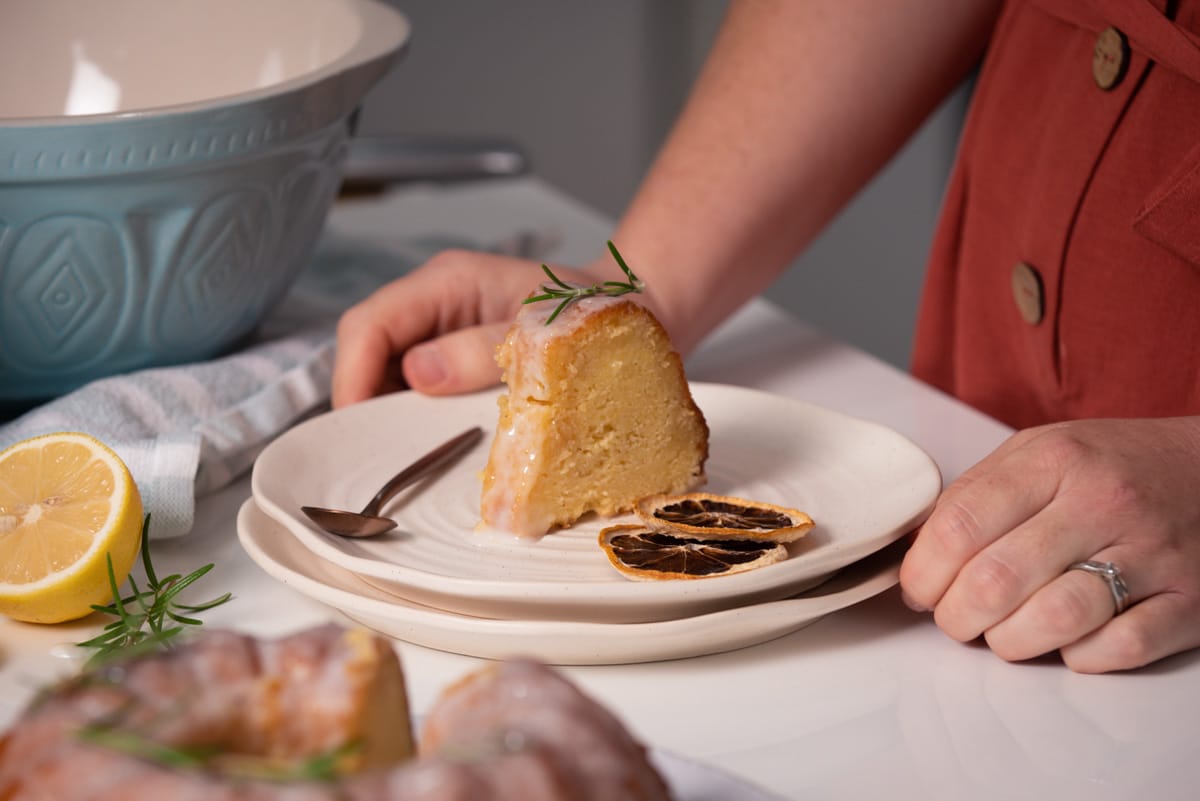 a piece of lemon cake on a white plate with hands