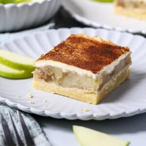 apple slice on a white plate topped with sour cream and cinnamon