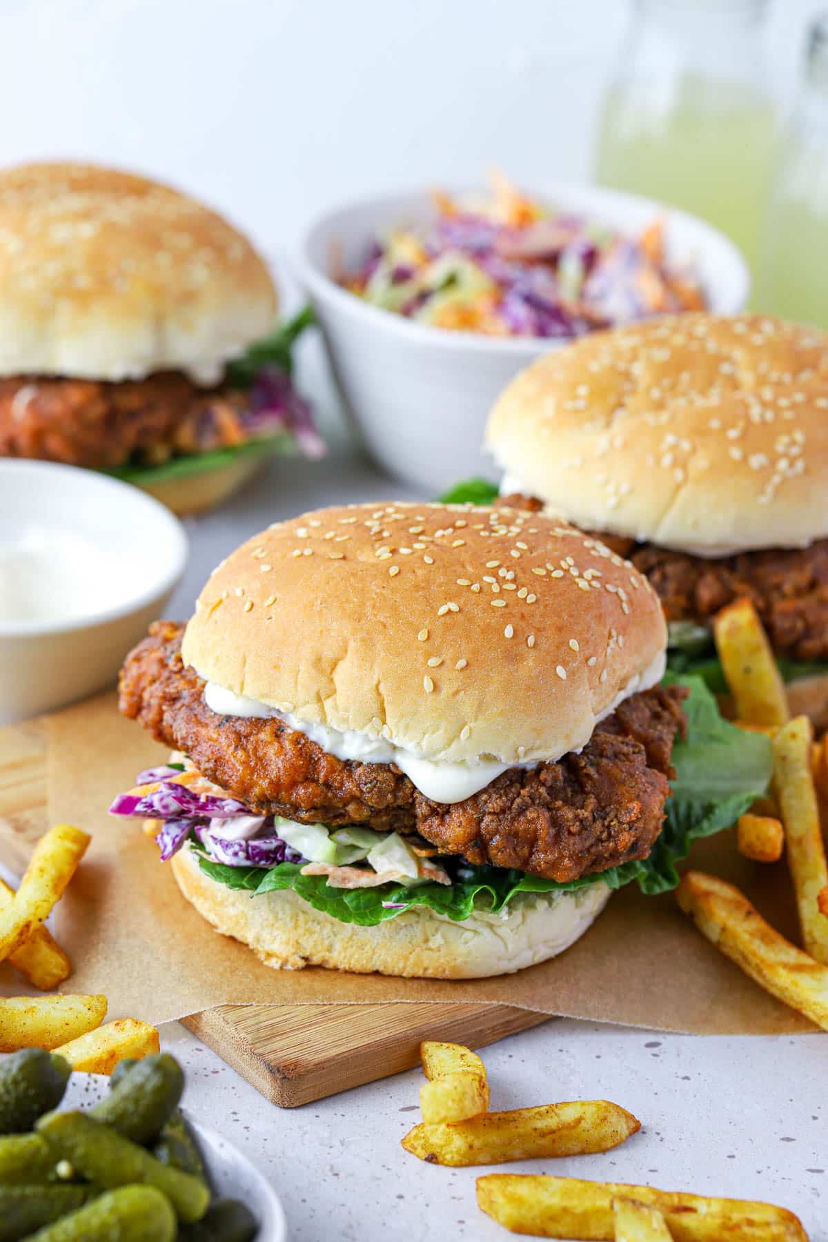 chicken burgers on a wooden board with coleslaw and fries