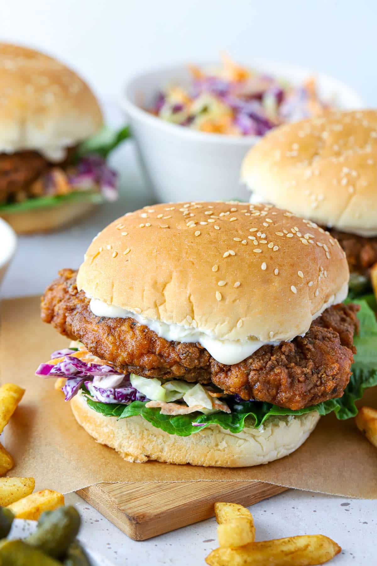 chicken burgers on a wooden board with fries and coleslaw