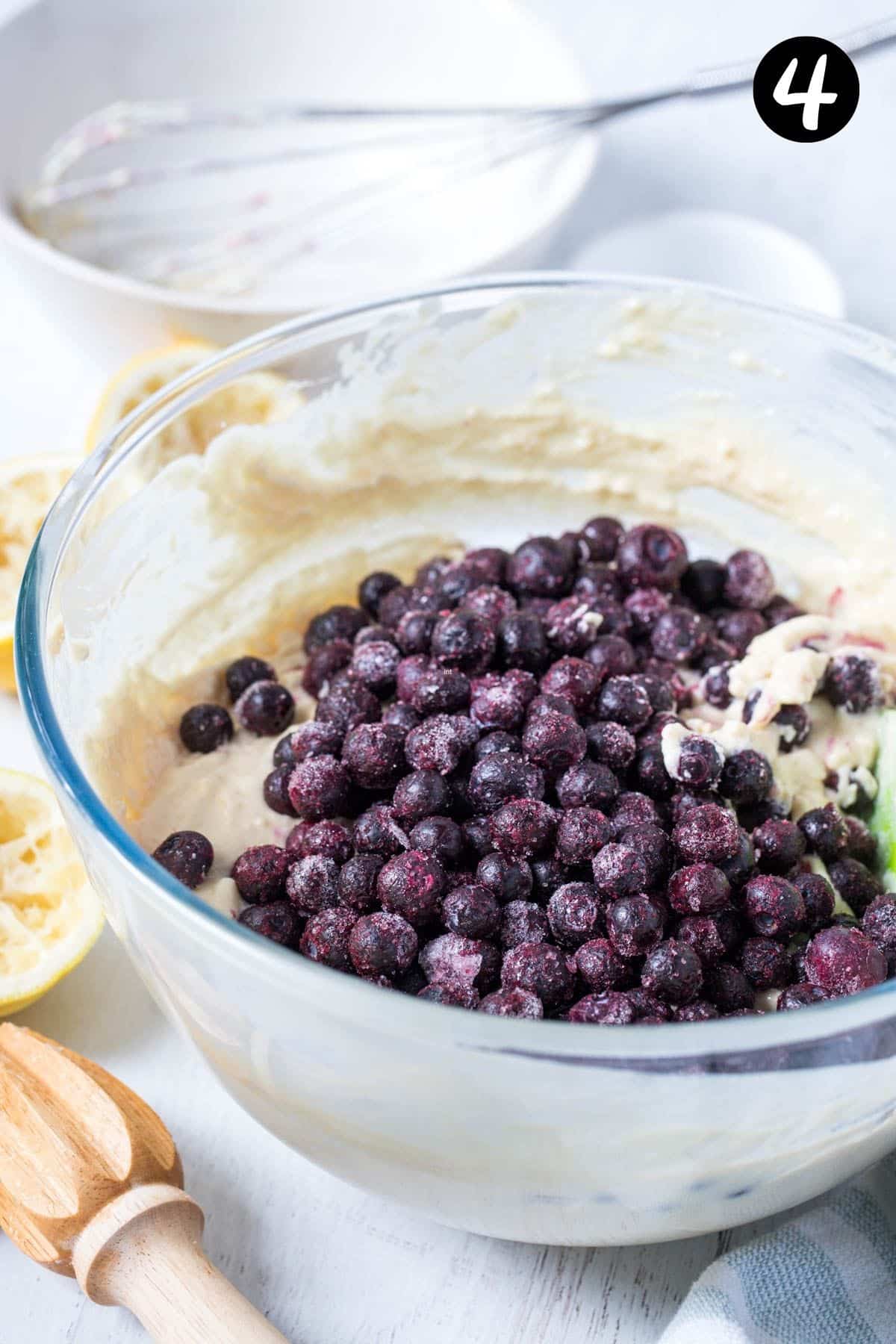 blueberries on top of muffin batter in a bowl.