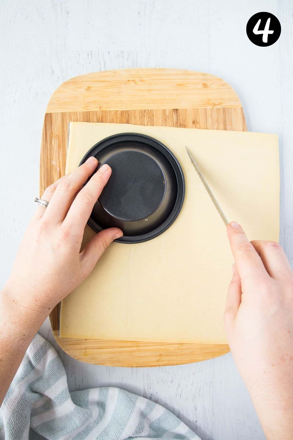 a hand cutting circles of pastry around a pie tin