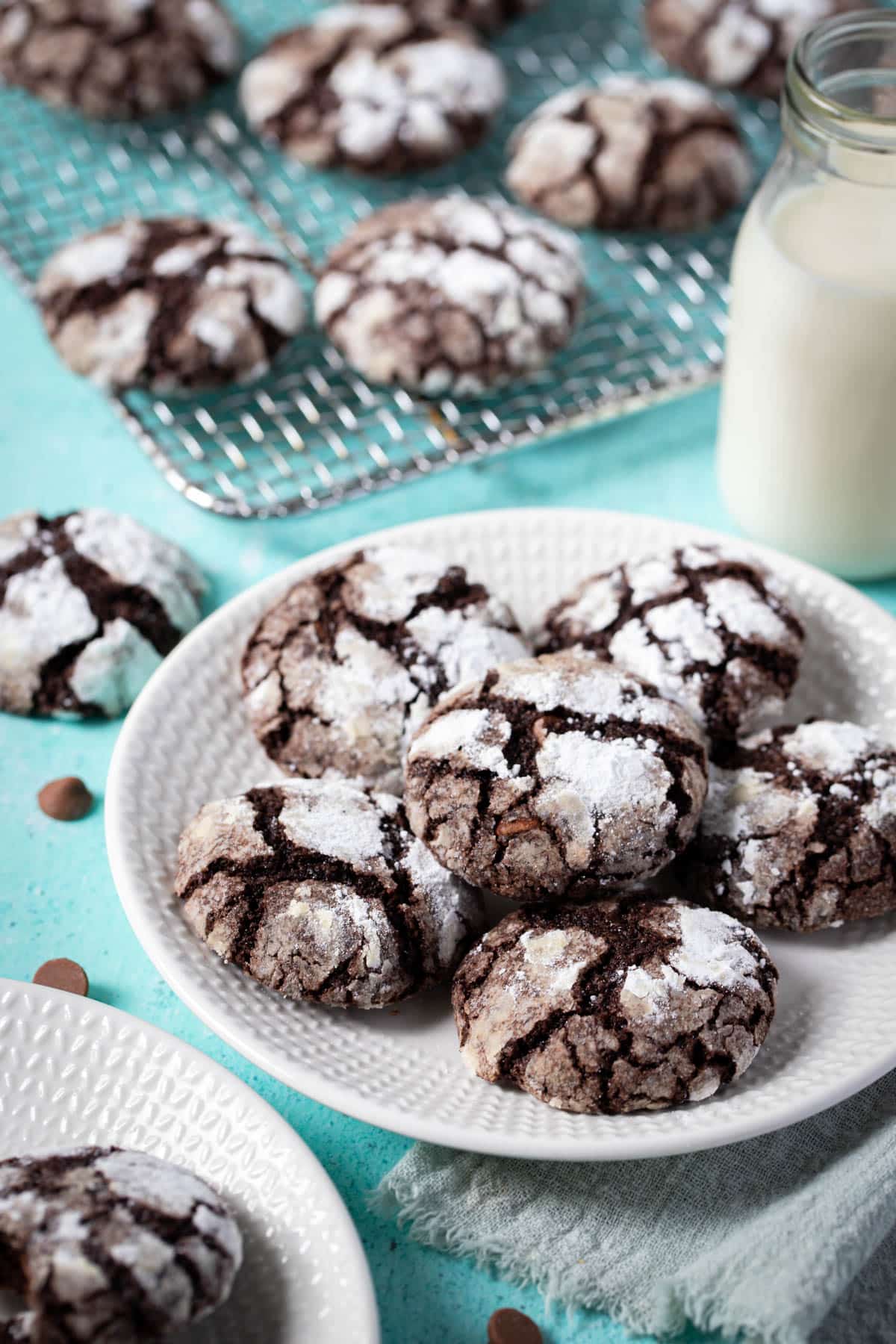 a plate of chocolate crinkle cookies on a blue table with milk