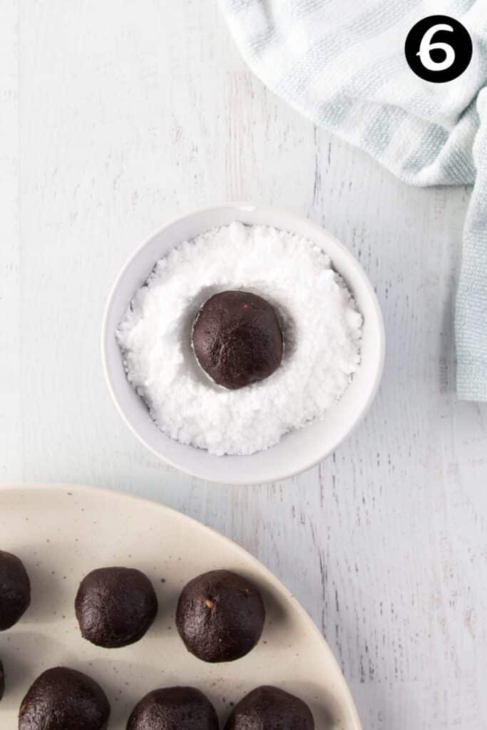 a cookie dough ball in a bowl of icing sugar