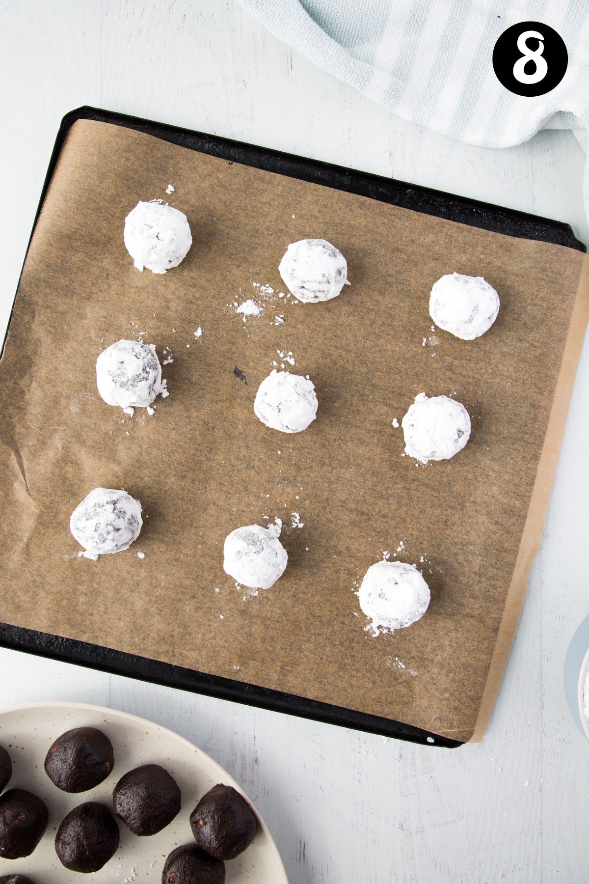 balls of cookie dough coated in icing sugar on a baking tray