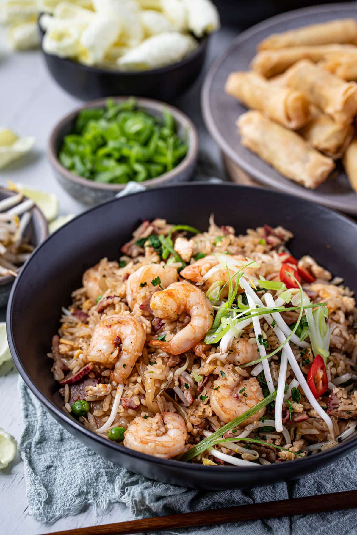 a bowl of fried rice topped with prawns, spring onion and bean shoots