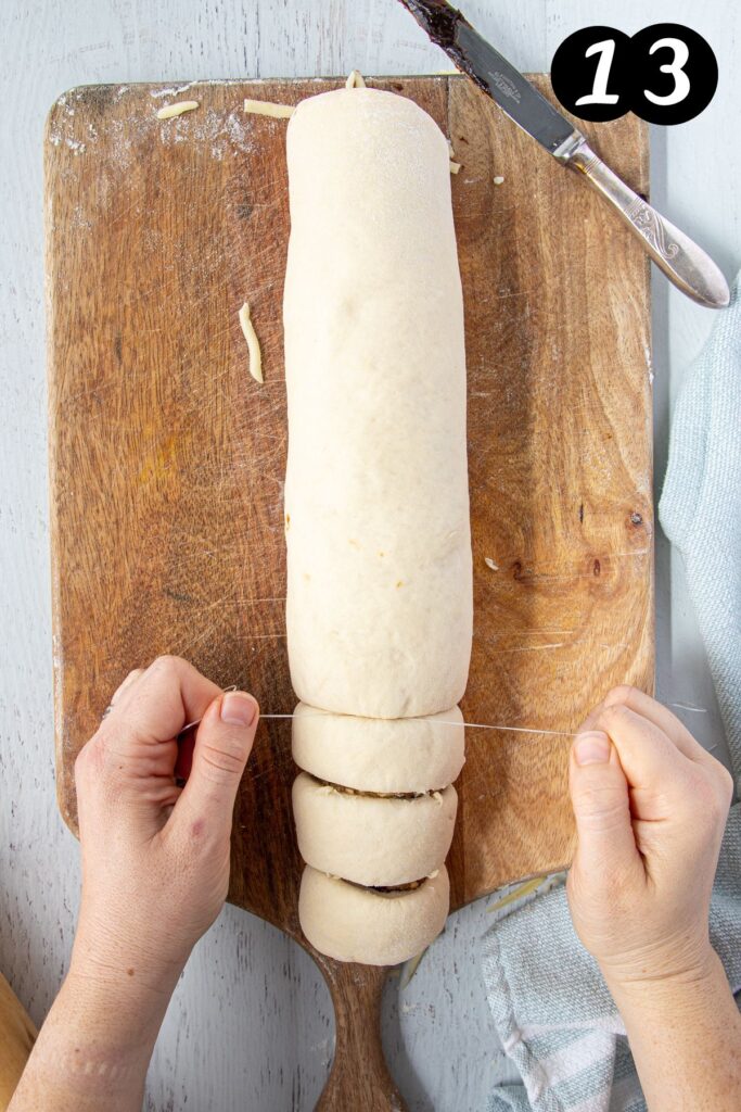 hands cutting a roll of dough into scrolls using floss.