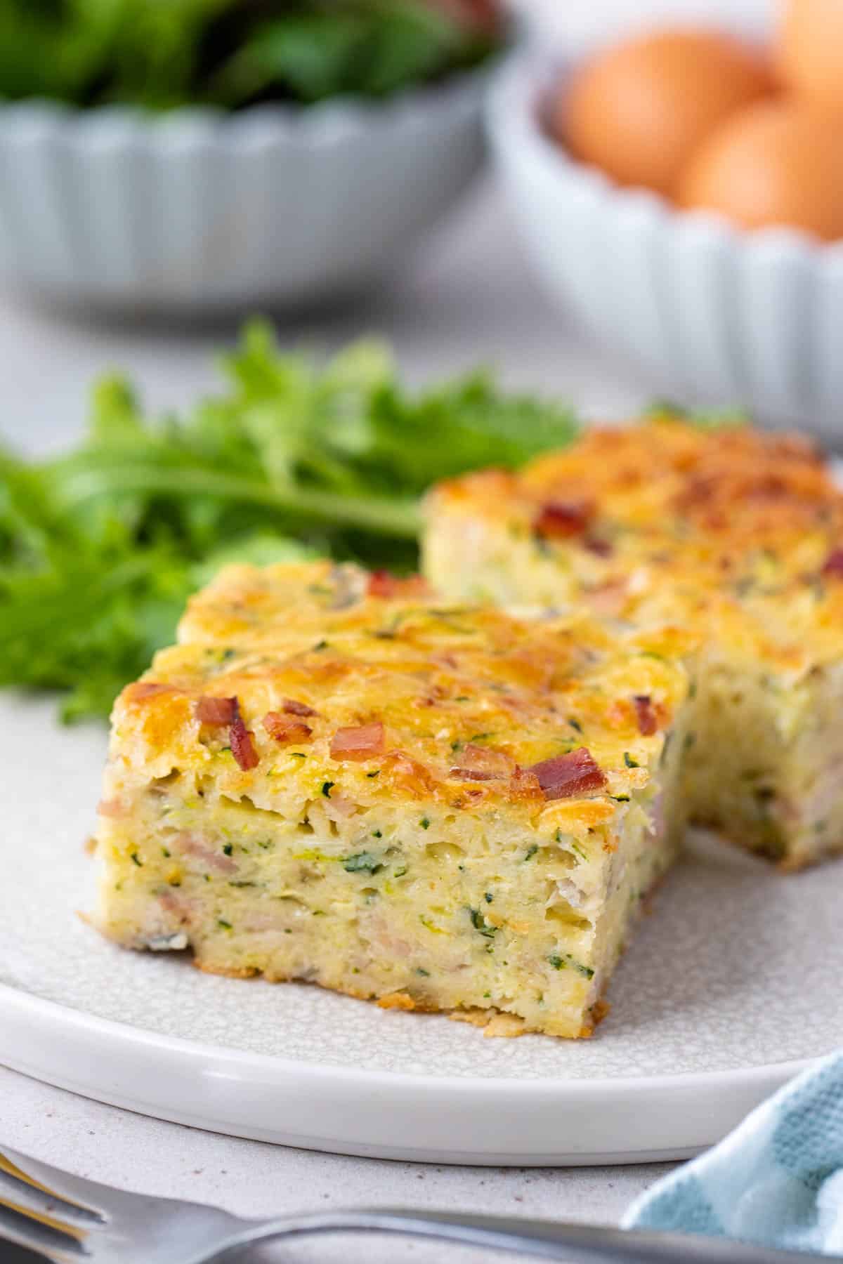 zucchini slice topped with bacon on a white plate.