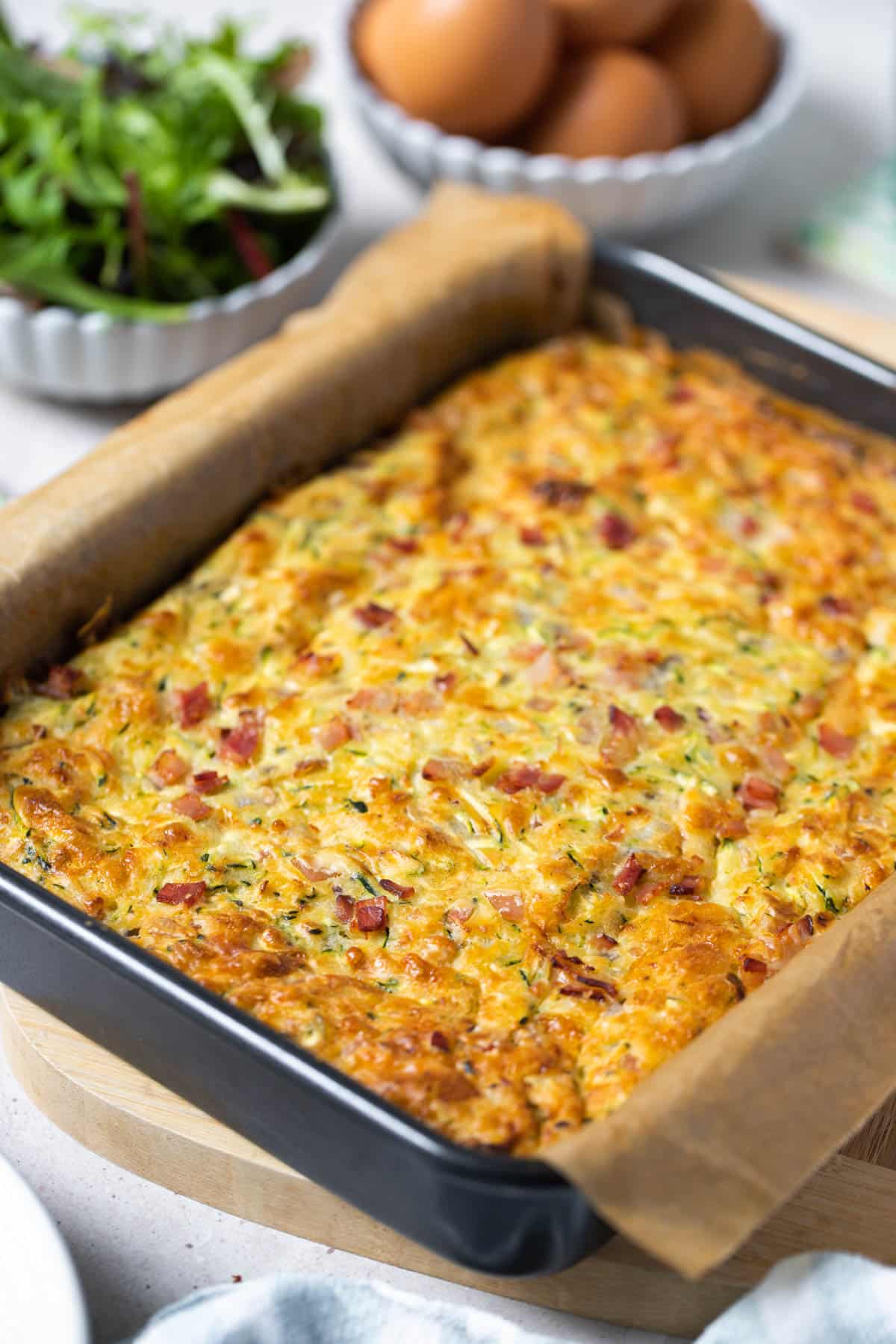 a whole zucchini slice in a baking tray with paper.