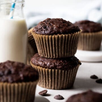 chocolate zucchini muffins on a table with chocolate chips.