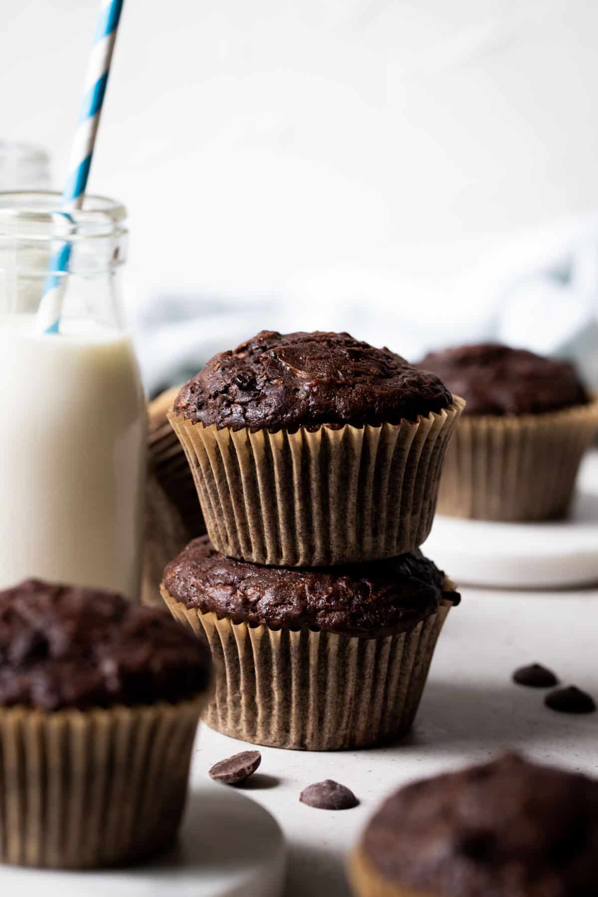 chocolate zucchini muffins on a white table with chocolate chips